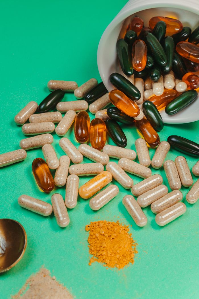 services-04 A collection of assorted capsules and powders spilled on a vibrant green surface, perfect for health-related content.